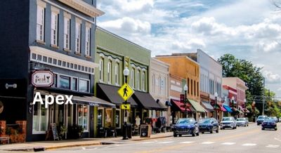 Quaint downtown Apex, NC, features colorful storefronts and a charming small-town vibe under a bright blue sky.